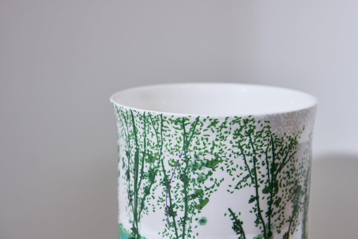 Ceramic vase with green plant pattern on a gray background