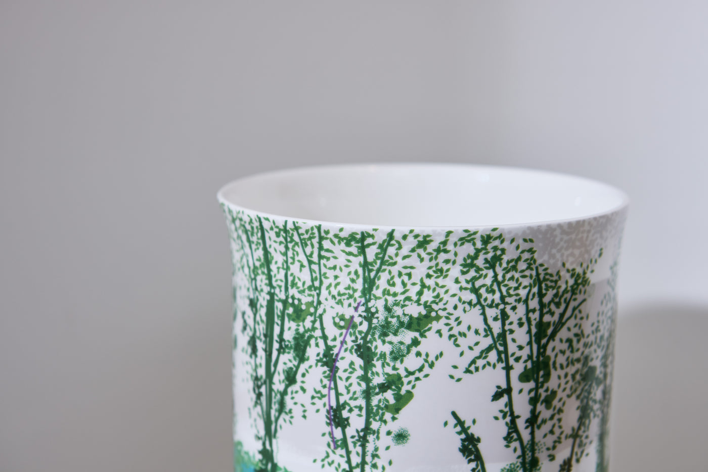 Ceramic vase with green plant pattern on a gray background